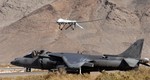 File - A U.S. Marine Corps AV-8B Harrier waits as a MQ-1 Predator lands Nov. 7, 2008, at Creech Air Force Base, Nev.