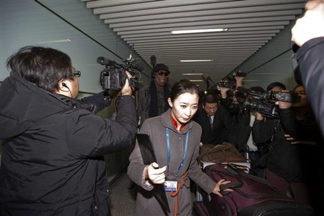 Former NBA star Dennis Rodman, center, evades journalists as he returns from a trip to North Korea at the airport in Beijing, Friday, March 1, 2013. Ending his unexpected round of basketball diplomacy in North Korea on Friday, Rodman called leader Kim Jong Un an "awesome guy" and said his father and grandfather were "great leaders." (AP Photo/Ng Han Guan)