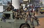 Government security forces in a pickup truck drive past a demonstration held by several hundred merchants calling for peace as negotiators prepare for talks with rebels from the north, in downtown Bangui, Central African Republic Saturday, Jan. 5, 2013.