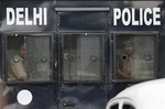 Indian policemen look out from a van carrying four men convicted in the fatal gang rape of a young woman on a moving New Delhi bus last year, in New Delhi, India, Tuesday, Sept. 10, 2013.