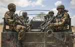 In this photo released by the African Union-United Nations Information Support Team, Kenyan soldiers serving with the African Union Mission in Somalia (AMISOM) sit on the back of a military vehicle as part of a re-supply convoy at their sector headquarters in the town of Dhobley, in southern Somalia, Sunday, Sept. 30, 2012.