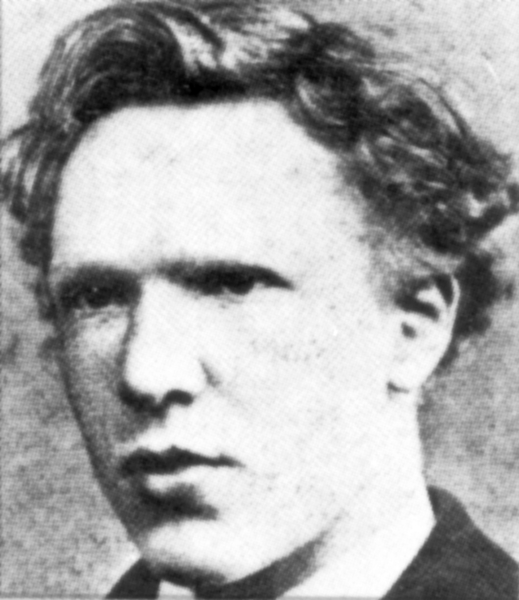 Headshot photo of the artist as a cleanshaven young man. He has thick, ill-kempt, wavy hair, a high forehead, and deep-set eyes with a wary, watchful expression.