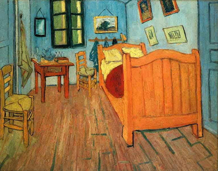 A narrow bedroom with wooden floor, green walls, a large bed to the right, a 2 straw chairs to the left, and a small table, a mirror and a shuttered window on the back wall. Hanging over the bed are several small pictures