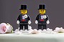 Two Lego men decorate the top of a wedding cake.
