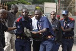 Security helps a wounded woman outside the Westgate Mall in Nairobi, Kenya Saturday, Sept. 21, 2013, after gunmen threw grenades and opened fire during an attack that left multiple dead and dozens wounded. A witness to the attacks on the upscale shopping mall says that gunmen told Muslims to stand up and leave and that non-Muslims would be targeted.