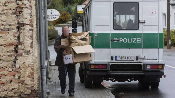 Ein Zivilpolizist trägt Beweismaterial aus dem Clubhaus der „Red Devils“ in Seelow (Landkreis Märkisch Oderland)