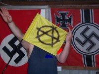 Daniel Klavins salutes in front of Nazi flags