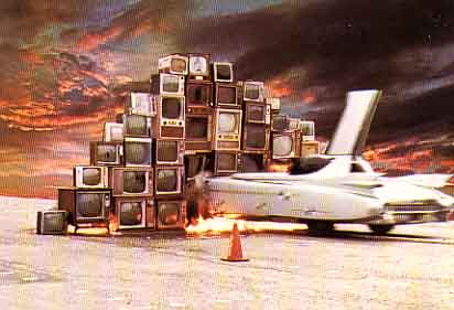 Media Burn, old burning cadillac plowing thru a wall of TV sets