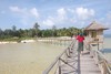 A woman walks the long wooden bridge along the beach shoreline - Surigao - philippines