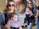 Precious cargo! Drew Barrymore's mini-me daughter Olive wears cute elephant themed shoes as her mother protectively cradles her in a baby carrier at the airport 