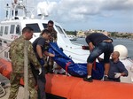 The body of a drowned migrant is being unloaded from a Coast Guard boat in the port of Lampedusa, Sicily, Thursday, Oct. 3, 2013.