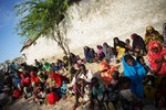 File - Somali men and women carrying their sick and malnourished children wait outside a medical clinic established by the African Union Mission in Somalia (AMISOM), an active regional peacekeeping mission operated by the African Union with the approval of the United Nations, 16 July, 2011.