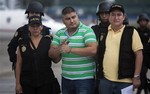 A man identified by Guatemala's government as Eduardo Francisco Villatoro Cano, alias "Guayo Cano," is escorted in handcuffs by police agents at an air force base in Guatemala City, Friday, Oct. 4, 2013.