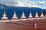 A tourist poses for a picture in front of stupa's and the Meili snow mountain range in Deqen county, Diqing Tibetan Autonomous Prefecture of southwest China's Yunnan Province.