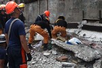 Rescuers shift through the rubble to recover an unidentified man at a fish port in Pasil, Cebu, central Philippines on Tuesday Oct. 15, 2013.