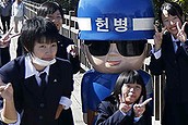 Japanese students pose for a photo with a statue of a South Korean military policeman