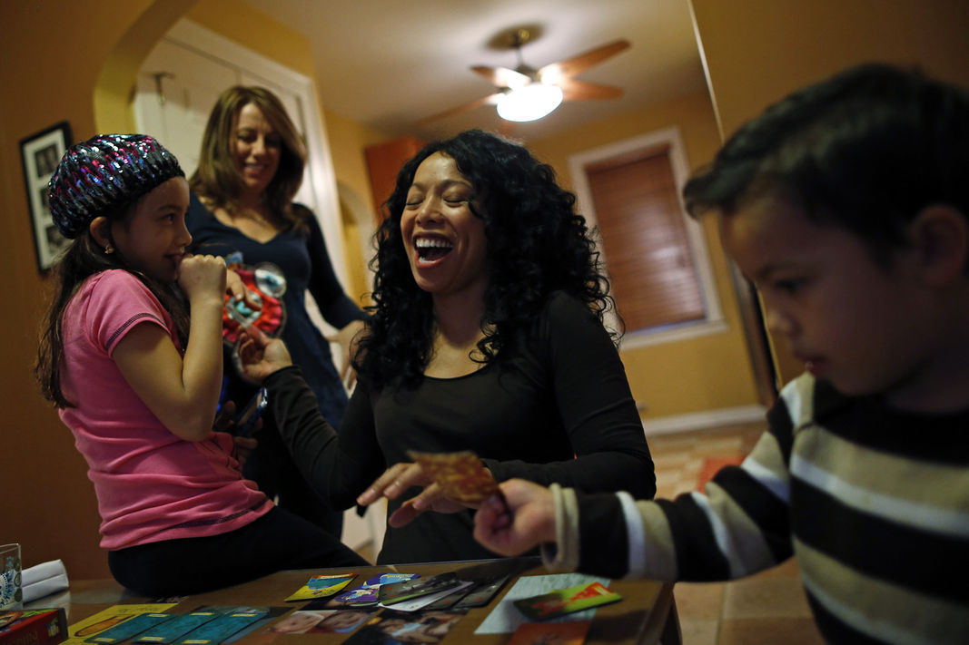 Mercedes Santos shares a laugh with her partner, Theresa Volpe, while playing cards with their kids at home in Chicago, Illinois, December 22, 2012.