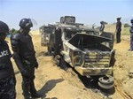 In this photo taken with a mobile phone on Monday, Oct. 28, 2013, police look down on a burnt out army personal carrier following an attack by Boko Haram in Damaturu, Nigeria.