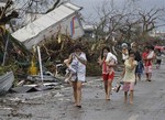 Residents cover their nose from the smell of dead bodies in Tacloban city, Leyte province central Philippines on Sunday, Nov. 10, 2013. The city remains littered with debris from damaged homes as many complain of shortage of food, water and no electricity since the Typhoon Haiyan slammed into their province.