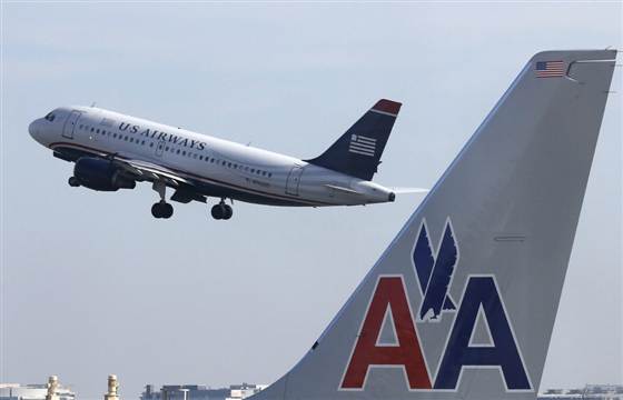 A US Airways jet departs Washington's Reagan National Airport next to American Airlines jets in this Feb. 25, 2013, file photo. US Airways Group Inc and American Airlines have agreed to give up landing spots and gates at several U.S. airports to win U.S. antitrust approval for their proposed merger, the Department of Justice said on Tuesday.