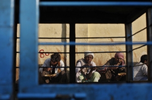 Men eat food provided by a charitable organisation, next to parked cycle rickshaws outside a...