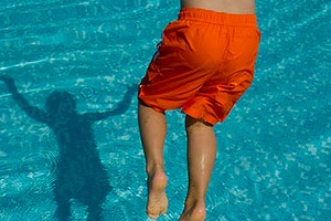 Boy jumping into swimming pool