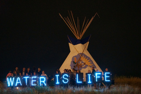 The Holders of the Light held several Idle No More water-related messages in front of the 2013 Indian Summer Festival’s tipi, prominently located on the State Park Island in front of the Indian Summer grounds. (Photo: Light Brigading / Flickr)