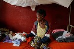 A severely malnourished child lays by his mother at Bangui's pediatric center in Bangui, Central African Republic, Tuesday Dec. 17, 2013.