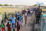 In this handout image from the United Nations Mission in South Sudan taken on Tuesday, Dec. 17, 2013 a United Nations soldier stands guard as civilians arrive at UNMISS compound adjacent to the Juba International Airport to take refuge.