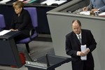 The top candidate of the German Social Democratic Party for the federal elections in the year 2013, Peer Steinbrueck, leaves the speakers podium during a meeting of the German Federal Parliament, Bundestag, in Berlin, Germany, Friday, Nov. 9, 2012. In the background is German Chancellor Angela Merkel.