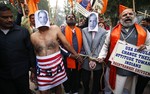 Supporters of right wing Rashtrawadi Shivsena, or nationalist soldiers of Shiva, walk with people representing U.S. President Barack Obama near the U.S Embassy to protest against the alleged mistreatment of New York based Indian diplomat Devyani Khobragade, in New Delhi, India, Wednesday, Dec. 18, 2013. The Indian diplomat said she faced repeated "handcuffing, stripping and cavity searches" following her arrest in New York City on visa fraud charges in a case that has infuriated the government in New Delhi. One of the persons representing Obama is naked to protest against the alleged stripping of the diplomat.