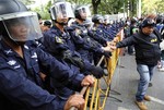 Thai anti-riot police stand guard next to a security guard for the anti-government protesters who stage a rally on the street outside the U.S. Embasy in Bangkok Thursday, Dec. 19, 2013.