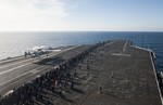 Sailors and tiger cruise participants watch an E-2C Hawkeye assigned to the Wallbangers of Carrier Airborne Early Warning Squadron 117 demonstrate a touch-and-go landing on the flight deck of the aircraft carrier USS Nimitz during an air power demonstration in the Pacific Ocean, 13 December, 2013.