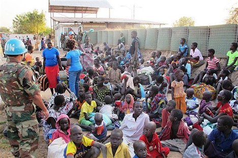 In this handout image provided by the United Nations Mission in South Sudan, taken on Tuesday, Dec. 17, 2013, a United Nation soldier stands guard as civilians arrive at the UNMISS compound adjacent to Juba International Airport to take refuge.