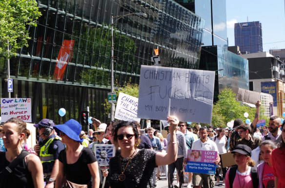 Pro-choice protester with placard at head of pro-life march