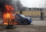 An al-Qaida fighter stands guard after setting fire to an Iraqi police truck in front of the provincial government headquarters in Fallujah, 40 miles (65 kilometers) west of Baghdad, Iraq, Wednesday, Jan. 1, 2014.