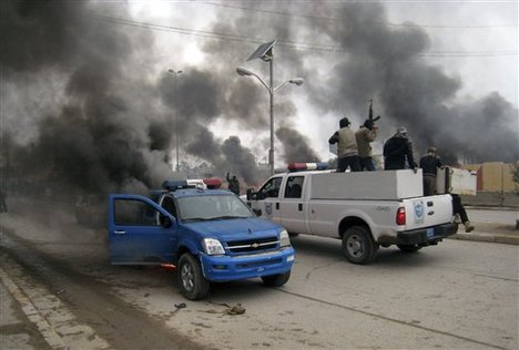 Al-Qaida fighters patrol in a commandeered police truck passing burning police vehicles in front of the main provincial government building, in Fallujah, 40 miles (65 kilometers) west of Baghdad, Iraq, Wednesday, Jan. 1, 2014.