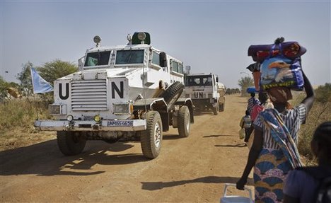 A United Nations armored vehicle passes displaced people walking towards the U.N. camp where they have sought shelter in Malakal, South Sudan, Monday, Dec. 30, 2013.