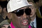 Former NBA basketball player Dennis Rodman, center, gestures to the media as he arrives at the departure hall of Beijing International Capital Airport in Beijing Monday, Jan. 6, 2014. Rodman says he's going forward with an exhibition game including former NBA players in North Korea because he wants to connect with its people and let others know the sheltered communist country isn't so bad. (AP Photo/Andy Wong)