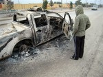 A man looks at a burned police vehicle in the main street of Fallujah after clashes between Iraqi security forces and al-Qaeda fighters in Fallujah, 40 miles (65 kilometers) west of Baghdad, Iraq, Sunday, Jan. 5, 2014.