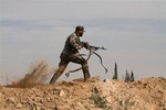 In this Friday, Nov. 22, 2013 file photo, a Shiite fighter clashes with members of the Sunni-dominated Free Syrian Army rebel in the town of Hatita, in the countryside of Damascus, Syria.