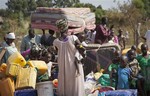 Refugees who fled the recent violence in South Sudan and crossed the border into Uganda carry their belongings as they await transportation from a transit center in the town of Koboko to a nearby settlement in Arua District, in northern Uganda Monday, Jan. 6, 2014.