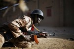 A Malian soldier takes cover behind a truck during exchanges of fire with jihadists in Gao, northern Mali, Sunday, Feb. 10, 2013.