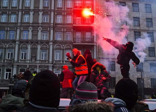 A protester throws a burning flare during clashes with police, in central Kiev.