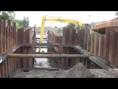 Digging out sheet pile cell with long stick backhoe