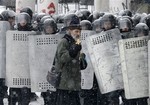 An Orthodox priest prays in front of police officers as they block a street after clashes in central Kiev, Ukraine, Wednesday, Jan. 22, 2014.