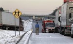 A man stands on the frozen roadway as he waits for traffic to clear along Interstate 75 Wednesday, Jan. 29, 2014, in Macon, Ga.