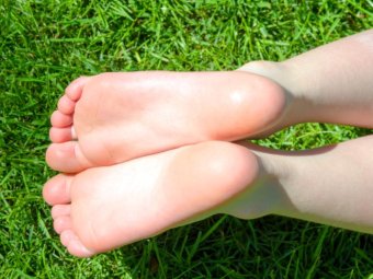 The soles of someone's feet lying in the grass