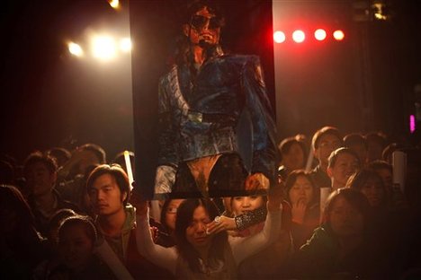 A fan of Michael Jackson cries while holding a poster with his likeness ahead of the premiere of the documentary "This Is It" in Beijing, China, Tuesday, Oct. 27, 2009