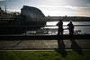 People stand on the north bank of the River Thames as the Thames Barrier stands open in calm weather, after closing for 13 successive tides up until Wednesday, in east London, Friday, Jan. 10, 2014.